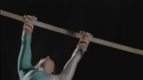 a woman performs a gymnastic routine on bars