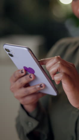 un primer plano de la mano de una mujer desplazándose por su teléfono con una pegatina de corazón púrpura.