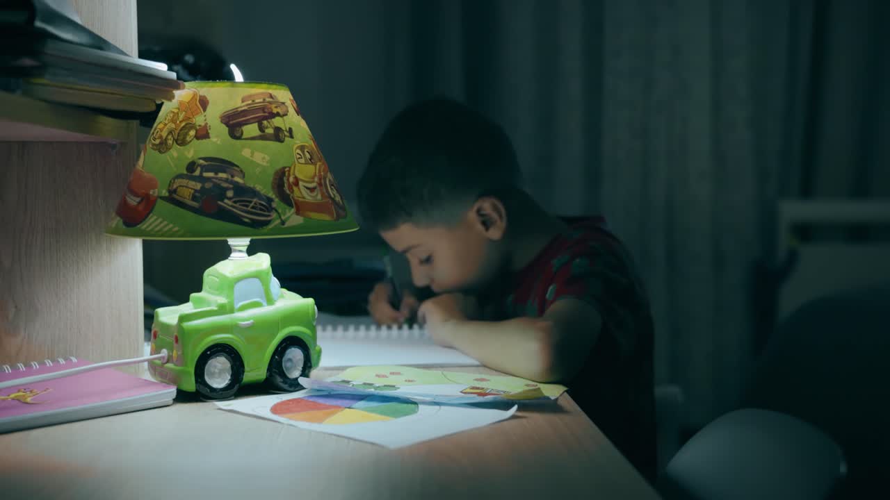 bambino che fa i compiti a casa di notte sulla sua scrivania