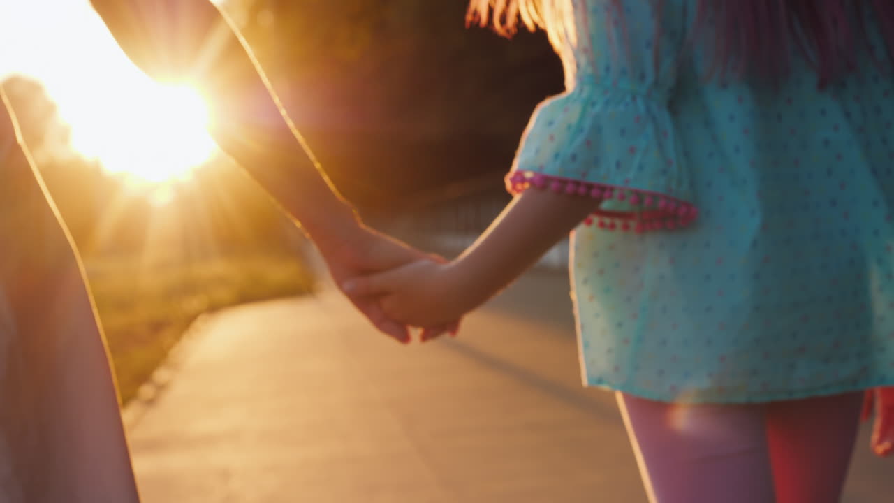 엄마는 석양의 행복한 어린 시절과 부모의 ca에서 골목 아래로 손으로 딸을 인도합니다.