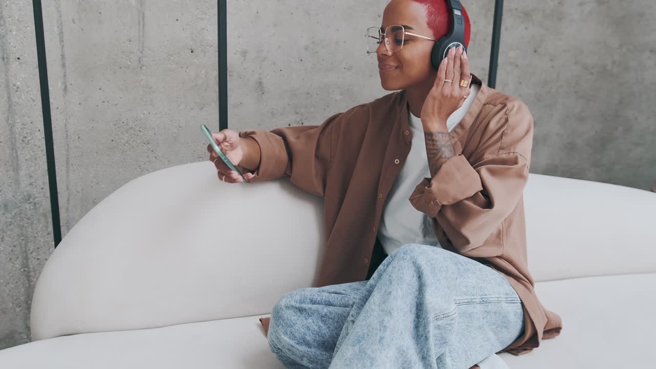 joven afroamericana escucha música con auriculares y sostiene el teléfono