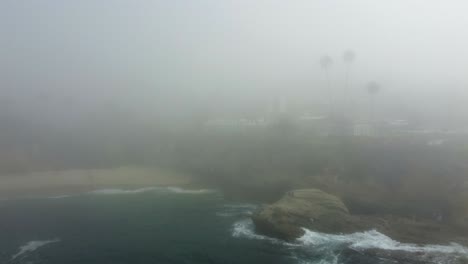 aerial view of thick morning fog above pacific ocean and cliffs of laguna beach and waterfront resort, california usa