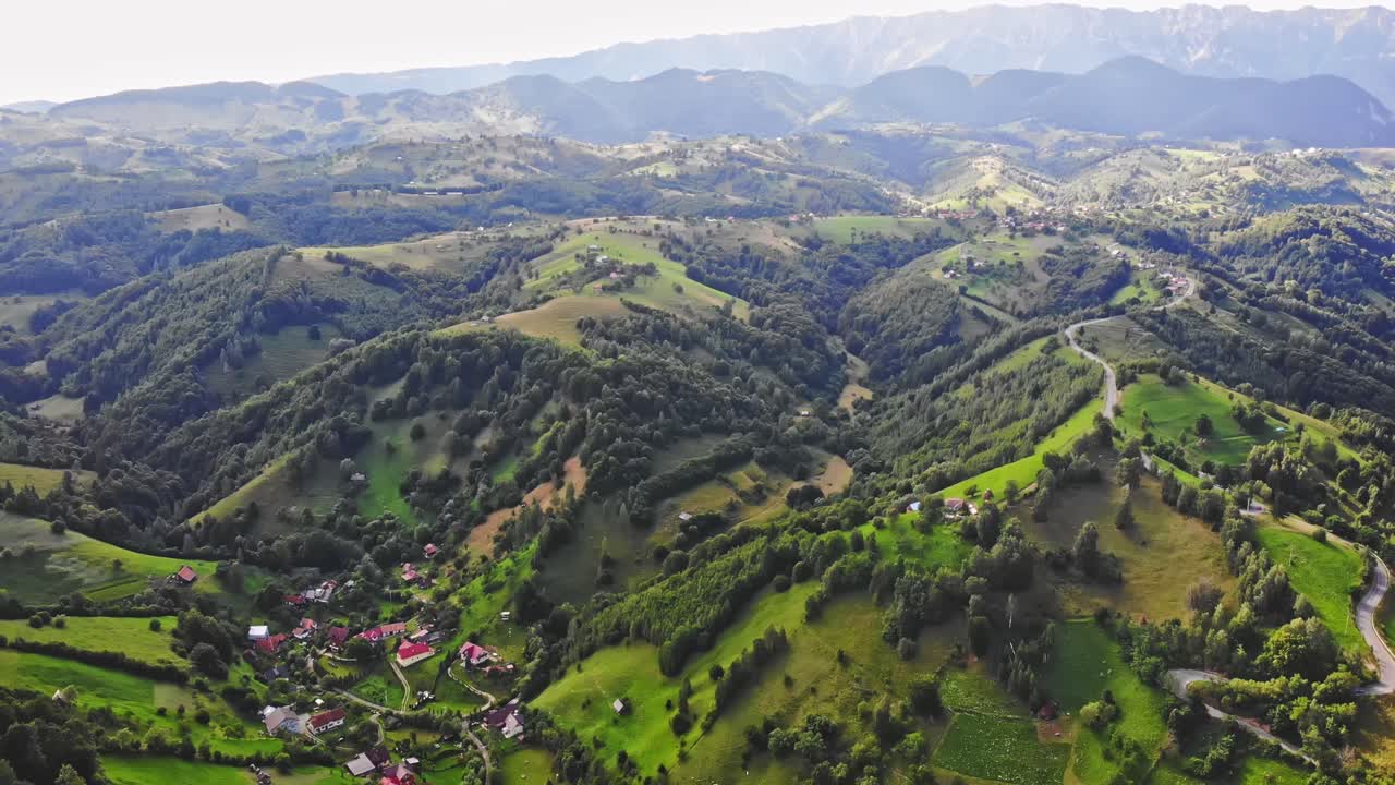 Aerial drone shot of a green forest, hills and houses in Brasov. Bird view