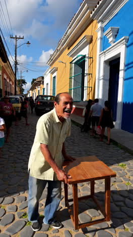 man interacting with a table on a vibrant cobblestone street with people and colorful buildings