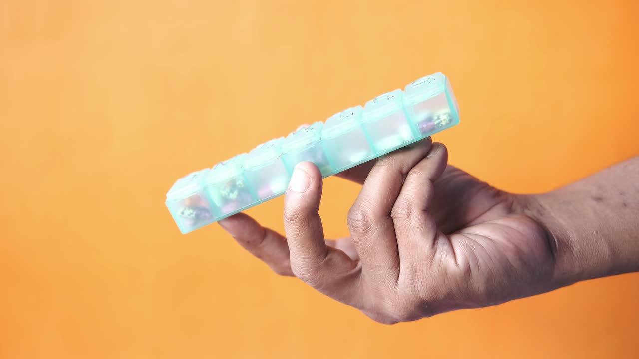 mão segurando um organizador de pílulas