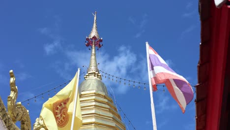 flags waving by a buddhist stupa under blue sky