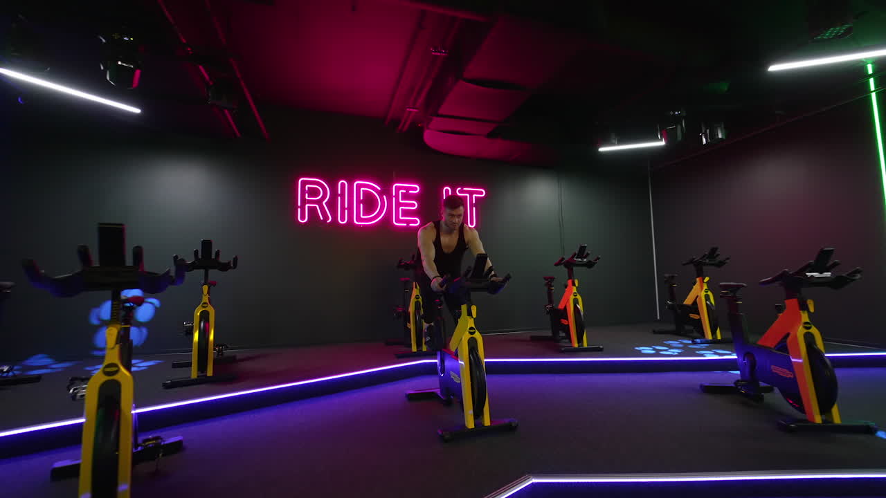 Man training on spin bike. Young man exercising legs doing cardio workout on cycling bike