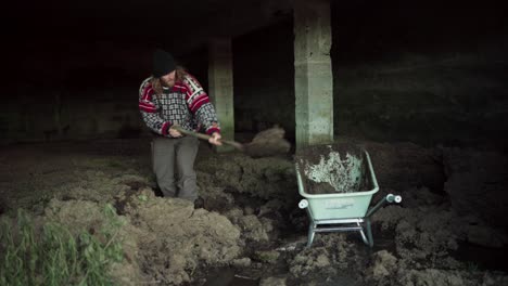 a man is filling the wheelbarrow with soil - static shot