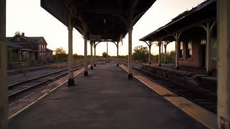 an empty train station comes to life as the sun sets, highlighting the faded architecture and nostalgic ambiance. trains no longer come, but the atmosphere retains its charm.