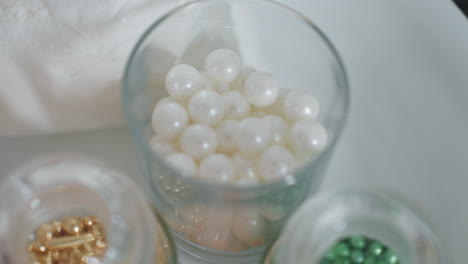 유리 컵에 색 진주 구슬과 작은 항아리에 보관된 금과 녹색 장식 구슬, 유리 잔에 설탕 결정, 베이킹 및 디저트 장식을 위해 끔하게 배열 된 클로즈업