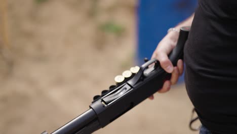 Guy-with-shotgun-reload-new-shotshells-into-barrel-chamber,-shooting-range