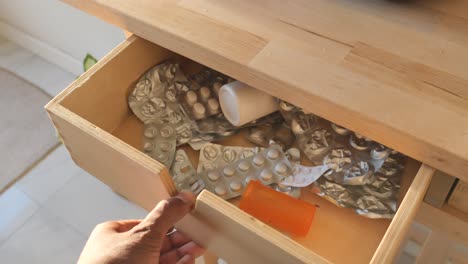 hand opening a messy medicine drawer