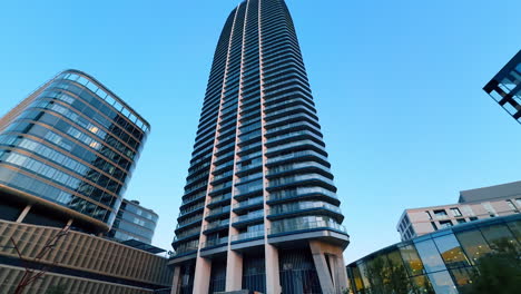 skyscraper looms over city. tall skyscraper dominates the skyline, surrounded by various buildings under a clear blue sky during sunset