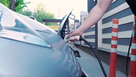 proceso de reabastecimiento de combustible de un automóvil eléctrico. un disparo debajo de la escotilla donde se carga el automóvil ecológico eléctrico. la escotella de carga del automóvil eléctrico se abre automáticamente. una mano masculina inserta un automóvil erecto