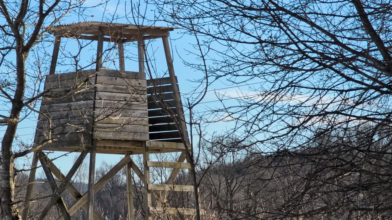 A wooden hunting tower on a meadow in the winter sun with clear blue sky. video shot in 60fps. This clip is 23,8 slowmotion so you can decide how you want it