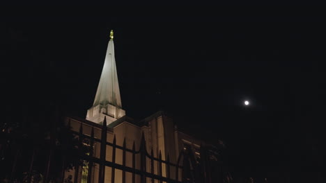 pájaros volando alrededor de la torre de un edificio de la iglesia del templo mormón lds en la noche con la luna en el fondo | gilberto, arizona