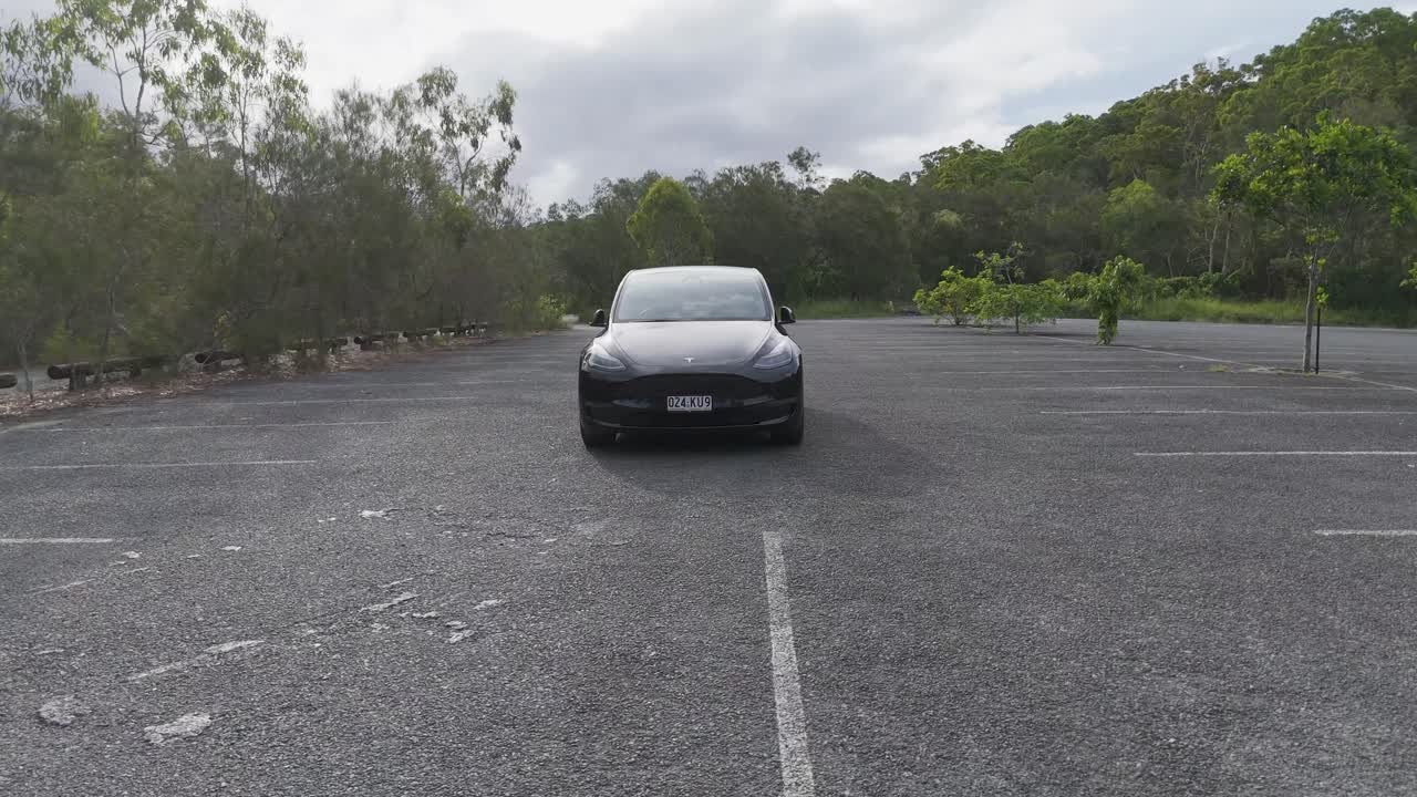 tesla modelo y negro estacionado en un estacionamiento vacío