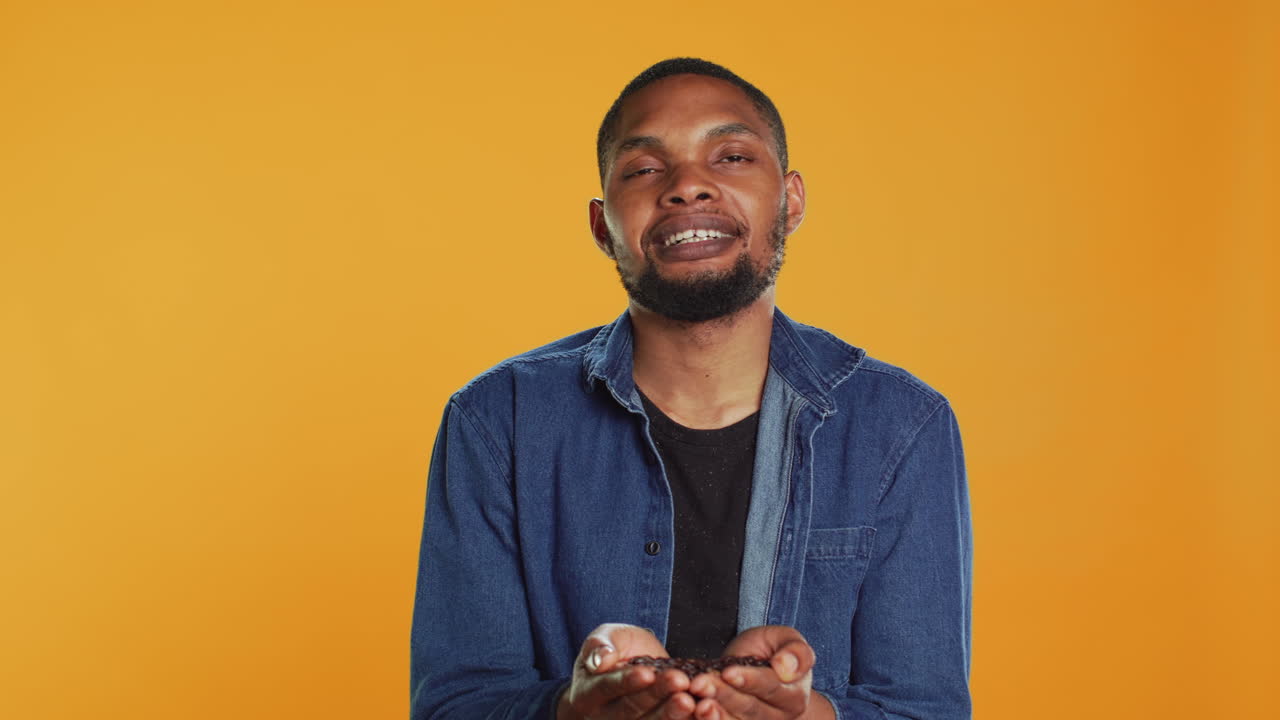 Coffee enthusiast looks at aromatic roasted beans against orange background