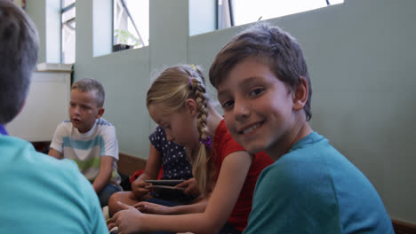 niño sonriendo mientras usa una tableta digital en la clase