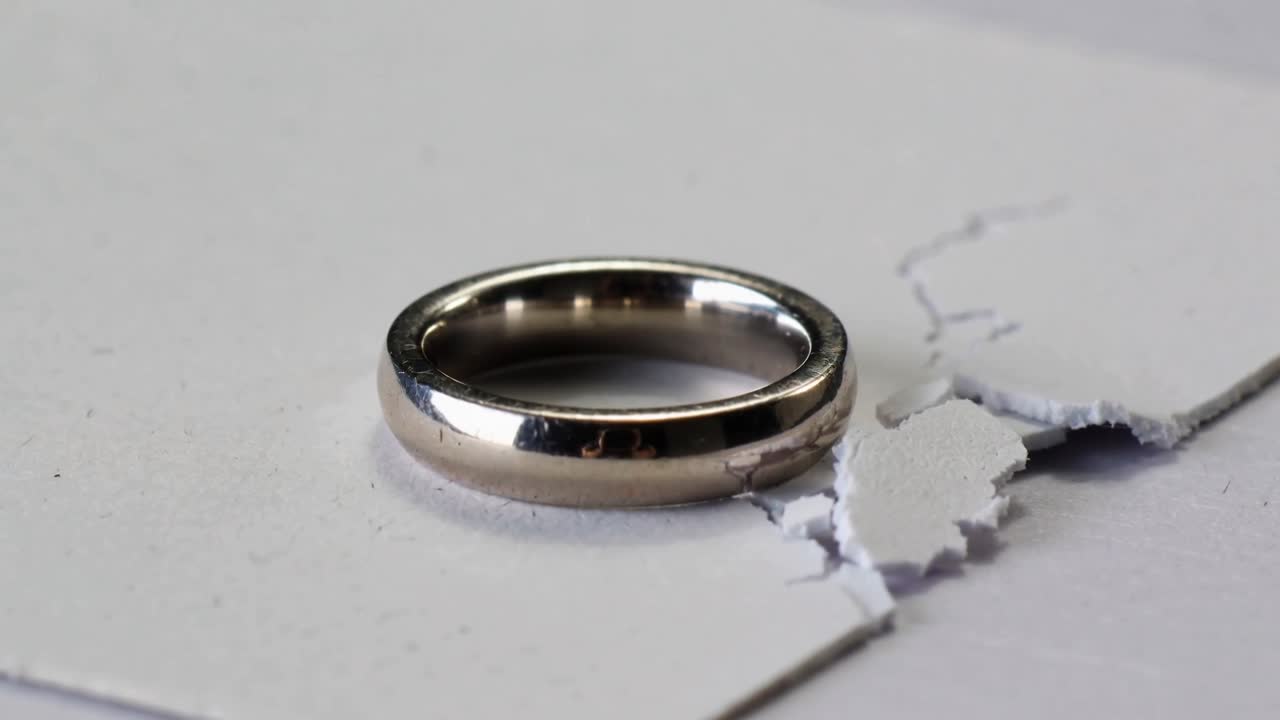 Panning camera moving down right, metal ring staying on torn cardstock, revealing paper fragments