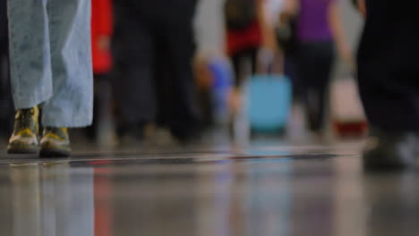 A man walks through the airport, then a woman with stylish shoes and bellbottoms