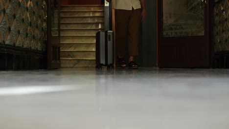 person walking with suitcase in hotel lobby