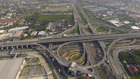 Vista-Aérea-Del-Cruce-De-Carreteras-Con-Tráfico-Urbano-Intenso-Acelerando-En-La-Carretera