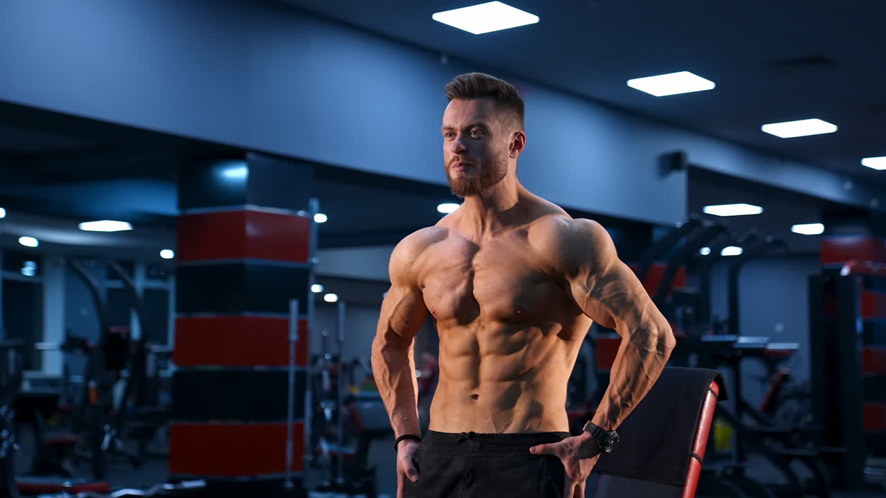 Brutal strong bodybuilder pumping up muscles. Bodybuilding and indoor sports concept. Slow motion.