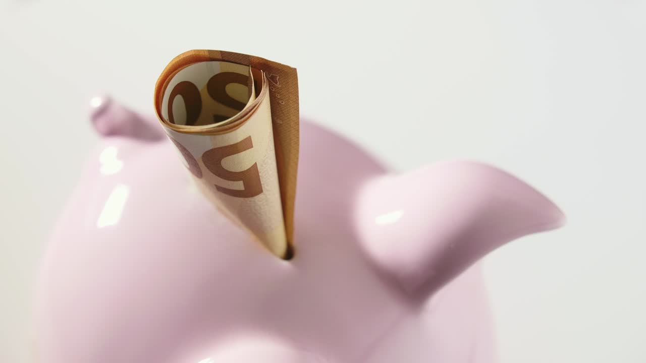 回転テーブル上の貯金箱に入ったユーロ紙幣の固定ショット