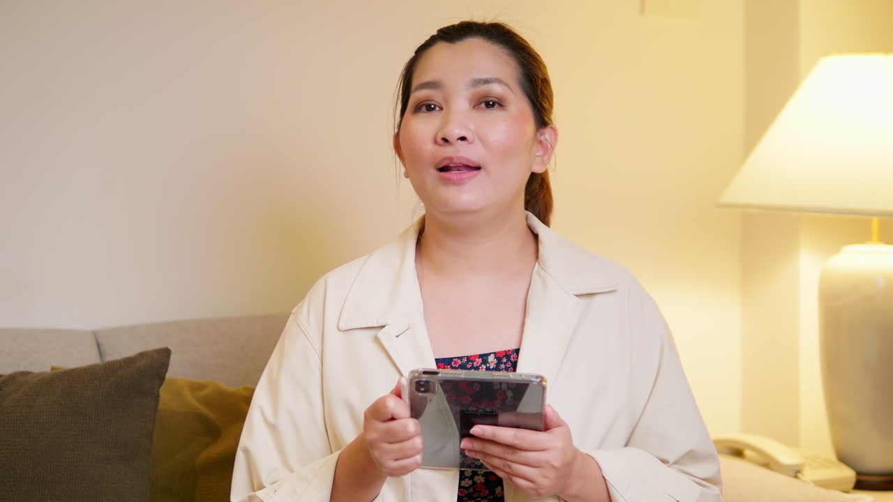 젊은 성인 여성이 평상복을 입고 방에서 말하는 비디오 온라인 커뮤니케이션을 설명하고 인터뷰합니다.