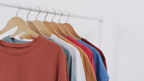 Video-of-selection-of-multi-coloured-t-shirts-on-hangers-and-copy-space-on-white-background