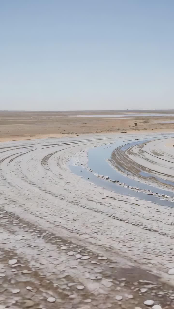 Vertical video: Panning camera moving across salt flat, showing curved channel and concentric arcs