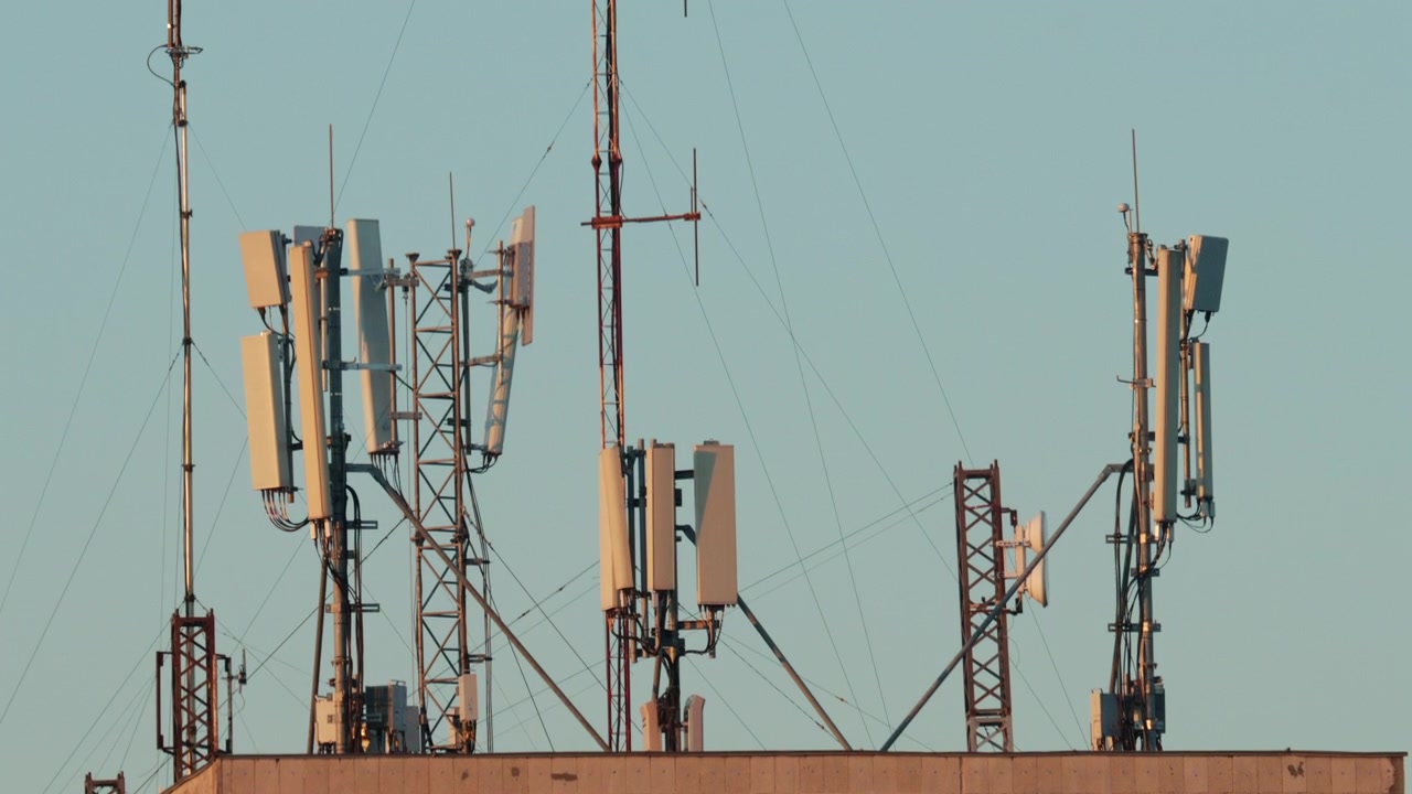 Close up of a telecommunications antenna mounted on a metal tower structure against a clear blue sky