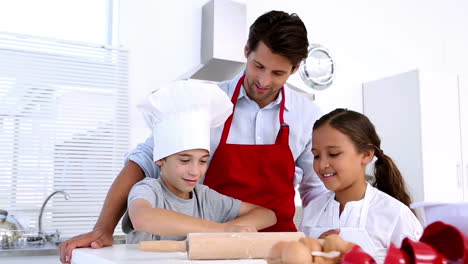 Father-watching-son-roll-pastry-with-sister