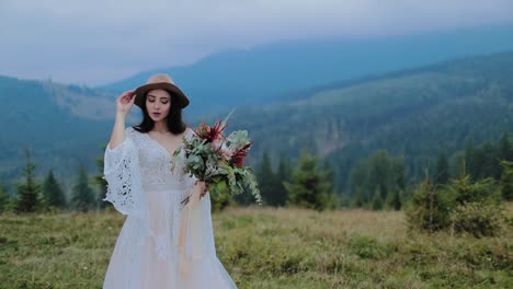 Stylish bride posing in mountains. Young and attractive woman dressed in wedding dress
