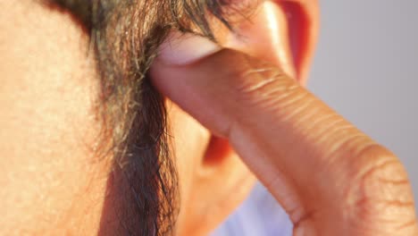 close-up of a man's hand touching his ear