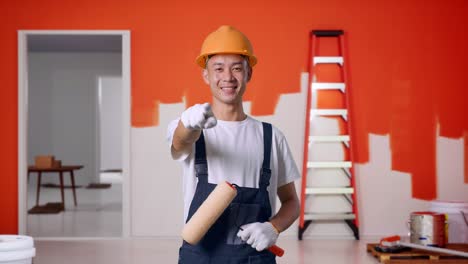pintor sonriente apuntando a la cámara en una habitación bajo renovación