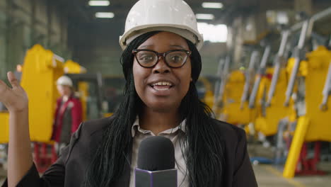 female tv journalist telling about heavy machinery factory on camera