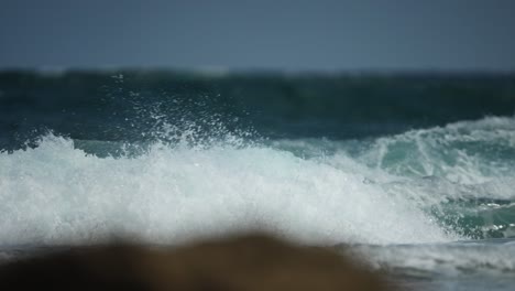 Wellen-Rollen-über-Den-Strand,-Wirbeln-Gischt-Auf-Und-Brechen-In-Die-Brandung-An-Lavasteinen-Vorbei