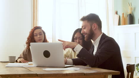 multiethnic business team sitting at table and having a debate while looking at laptop computer