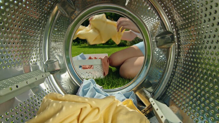 Person Loading Laundry in Washing Machine Outdoors