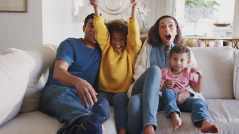 Young-African-American-family-sitting-together-watching-a-movie-accidentally-throwing-popcorn-in-the-air