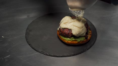 Chef-En-Restaurante-Gourmet-Queso-Derretido-Sobre-Solomillo-Premium-Carne-De-Solomillo-Para-Hamburguesa-Sobre-Plato-De-Piedra-Raclette-Caliente