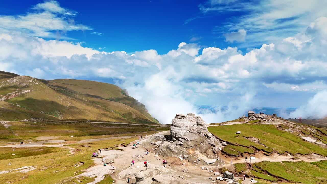 Stunning rocky mountain views. Green hills and a blue sky with clouds frame unique rock formations, inviting adventure and exploration