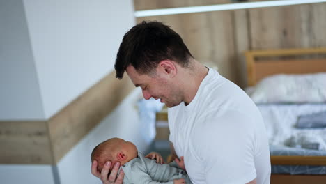 happy new-made dad with a newborn in hands. father waving his newborn in hospital ward.