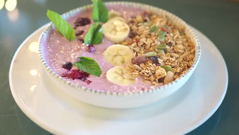 eating a healthy smoothie bowl with granola, banana, and berries
