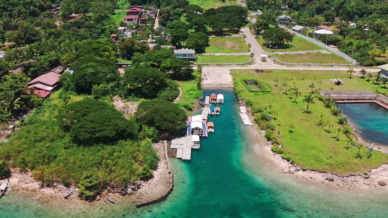 Vibrant aerial drone footage of a tropical marina with boats, turquoise waters, and a coastal village in the Philippines. Perfect for travel, tourism, and real estate projects