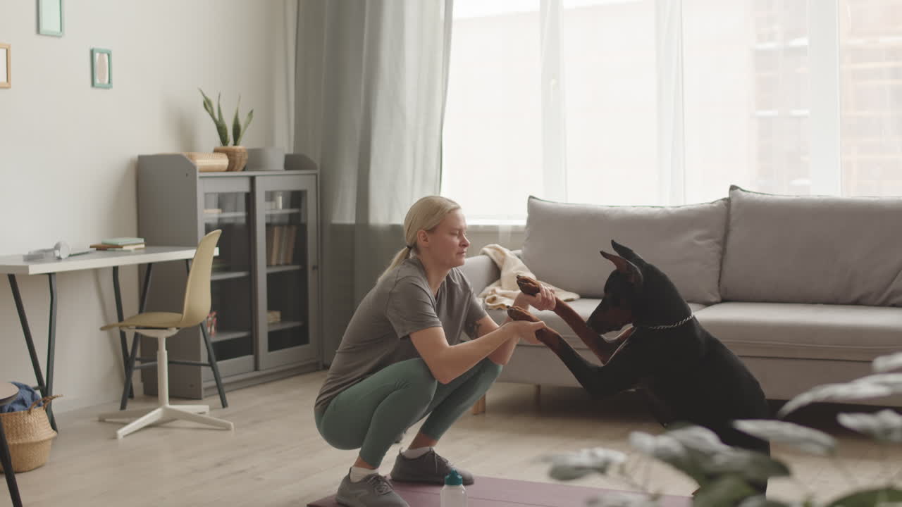 Sportswoman Doing Squats with Doberman