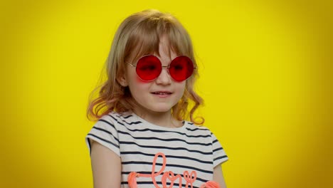 playful happy kid girl in sunglasses blinking eye, looking at camera with smile, winking, flirting