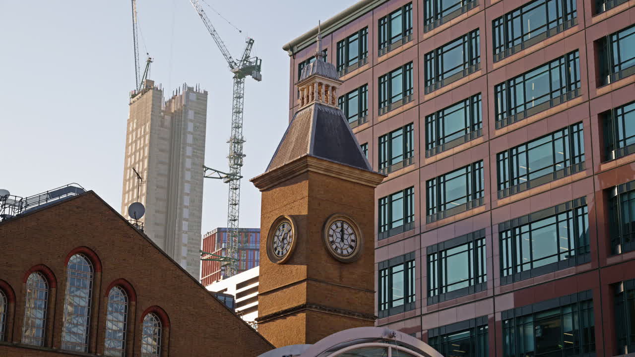 Close up of the clock tower at Liverpool Street Station with construction cranes and modern buildings in the background in London, England